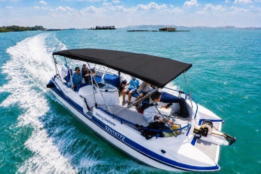 A white and blue boat named 'Kelving Explorer' with a black canopy, moving on turquoise water with a wake behind it. 1