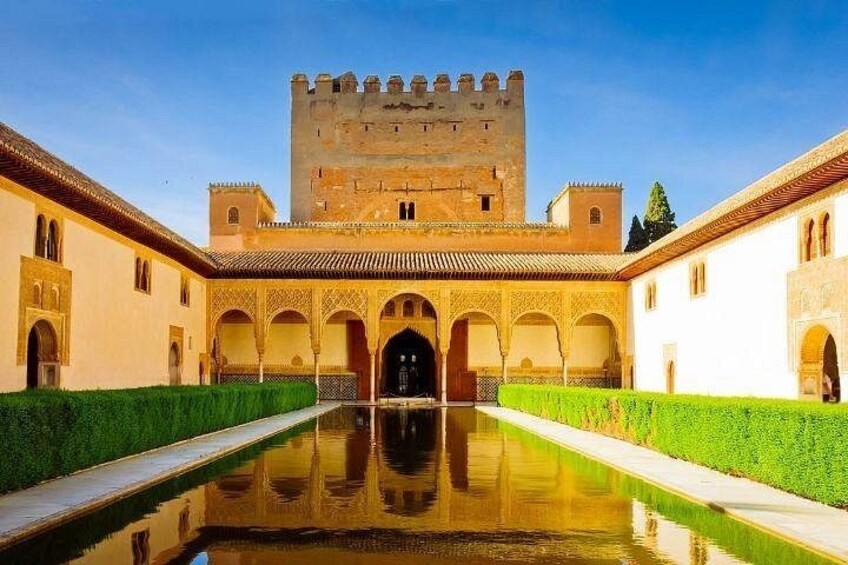 A courtyard with a reflective pool, arches, and a castle-like structure in the background. 1