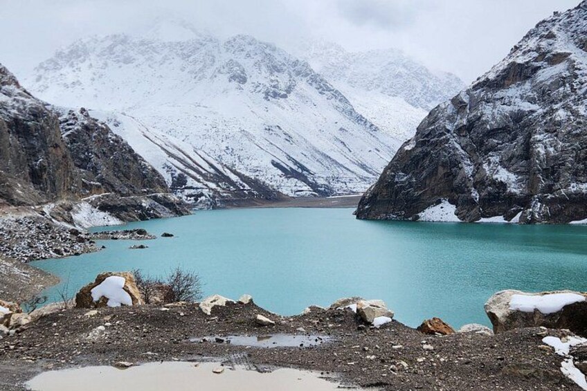 A turquoise lake surrounded by snow-covered mountains. 2