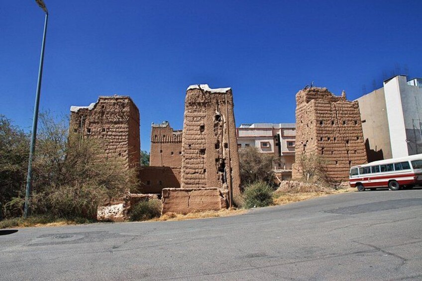 Ancient brick ruins, a clear blue sky, and a red and white bus on a road. 4