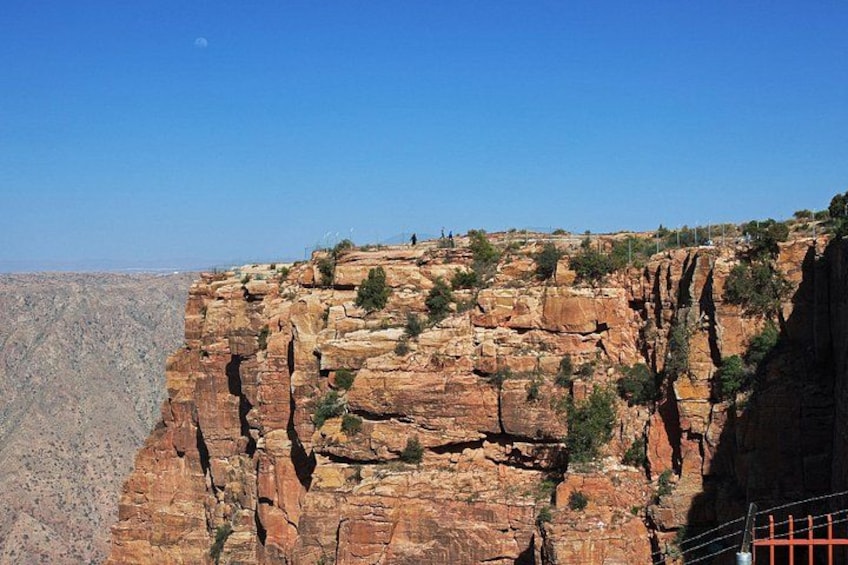 A canyon with layered rock formations and sparse vegetation. 3