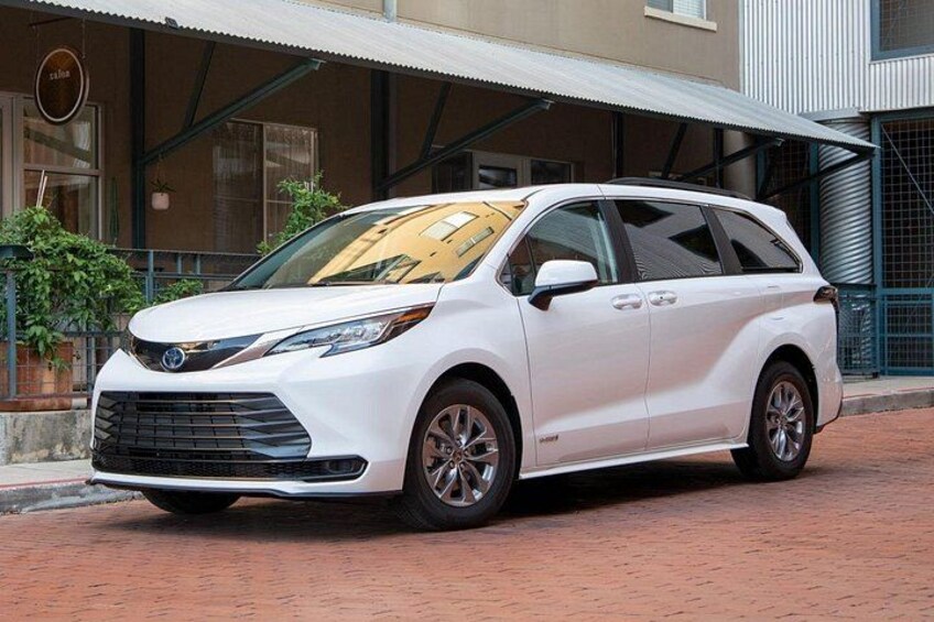A white SUV parked on a brick pavement in front of a building with a metal awning. 2
