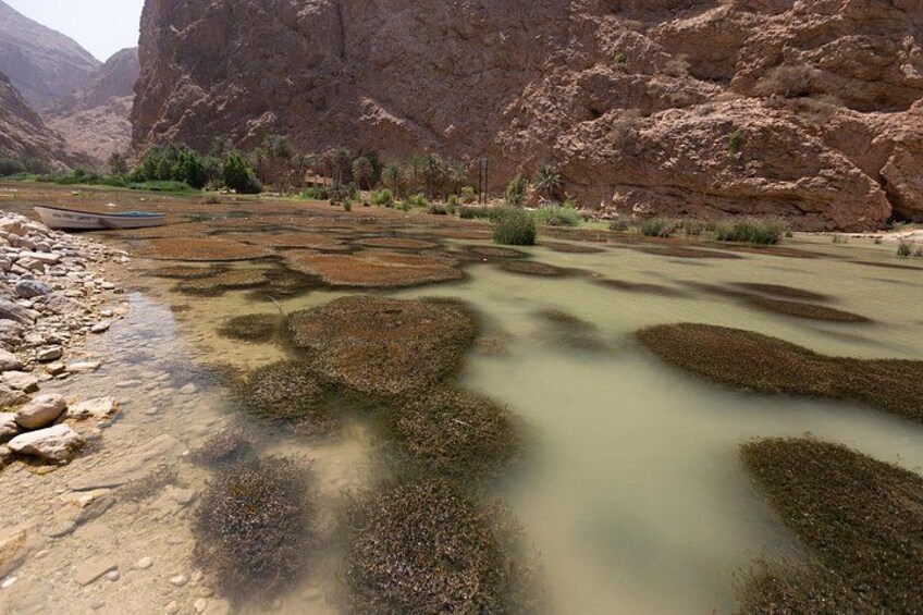 A river with clear water, rocky banks, and a boat. 5