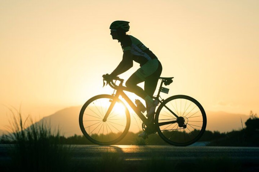Un cycliste pédalant sur une route au coucher du soleil. 2