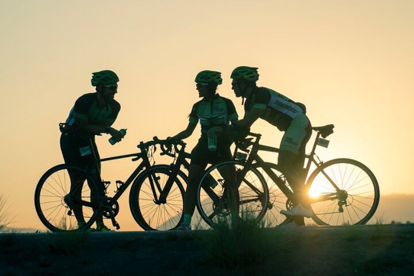 Three cyclists on a road at sunset. 1