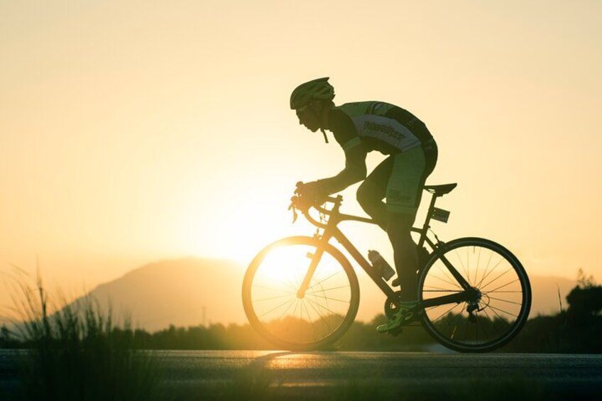 A cyclist riding a bicycle on a road during sunset. 4
