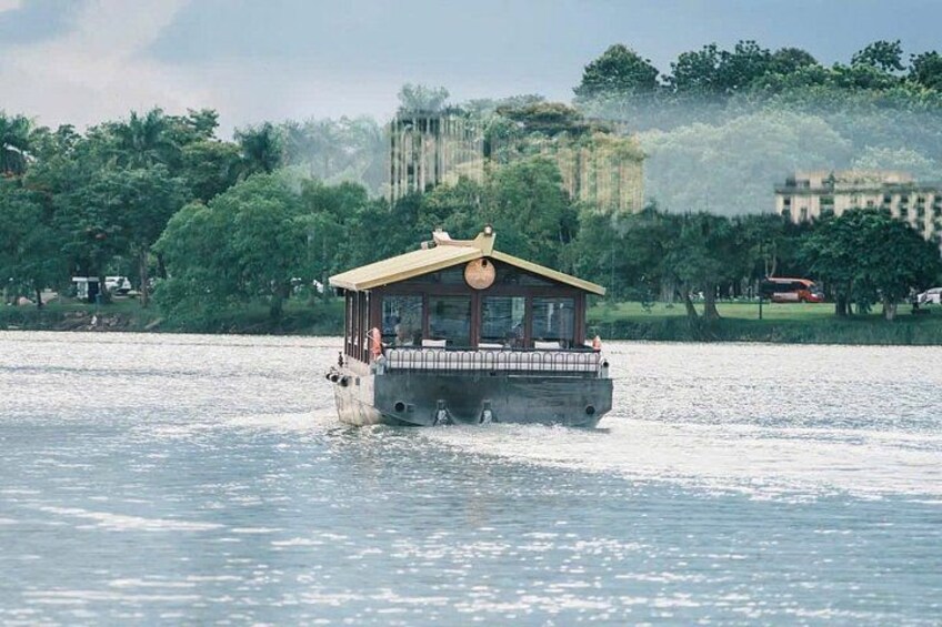Une maison flottante sur l’eau, avec un toit jaune, entourée d’arbres et de bâtiments. 2