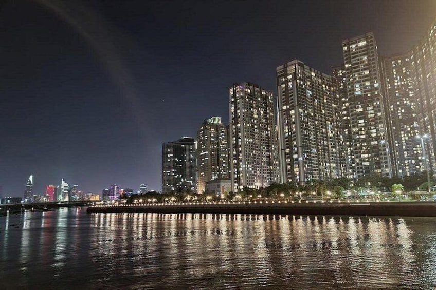 A nighttime cityscape with illuminated high-rise buildings reflecting on a body of water. 2