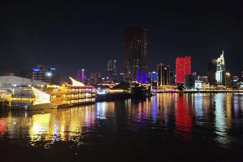 A city skyline at night with illuminated buildings and a river reflecting lights. 2