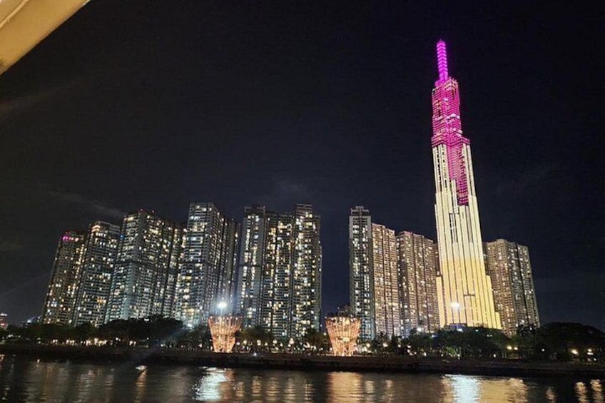 A city skyline at night with illuminated buildings and a prominent tower with pink lights. 3