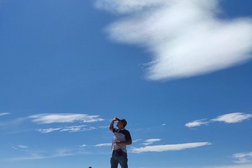 Una persona de pie con los brazos levantados hacia un cielo azul despejado. 3