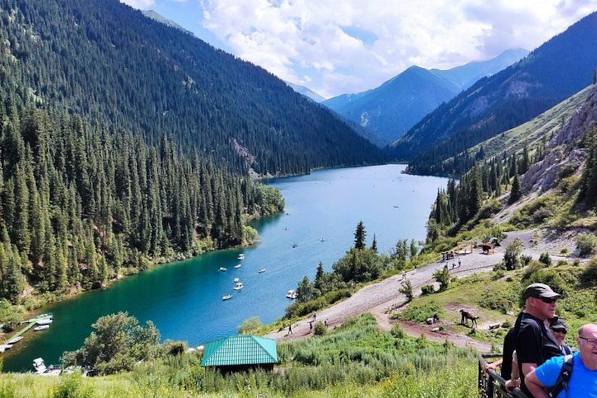 Un lago rodeado de montañas boscosas, un pequeño embarcadero y algunas embarcaciones. 1