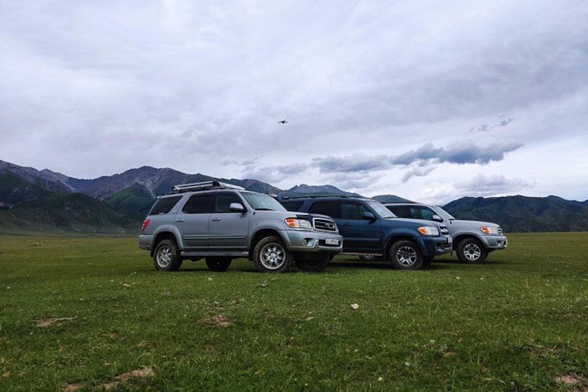 Tres SUVs estacionados en un campo cubierto de hierba, con montañas al fondo. 4