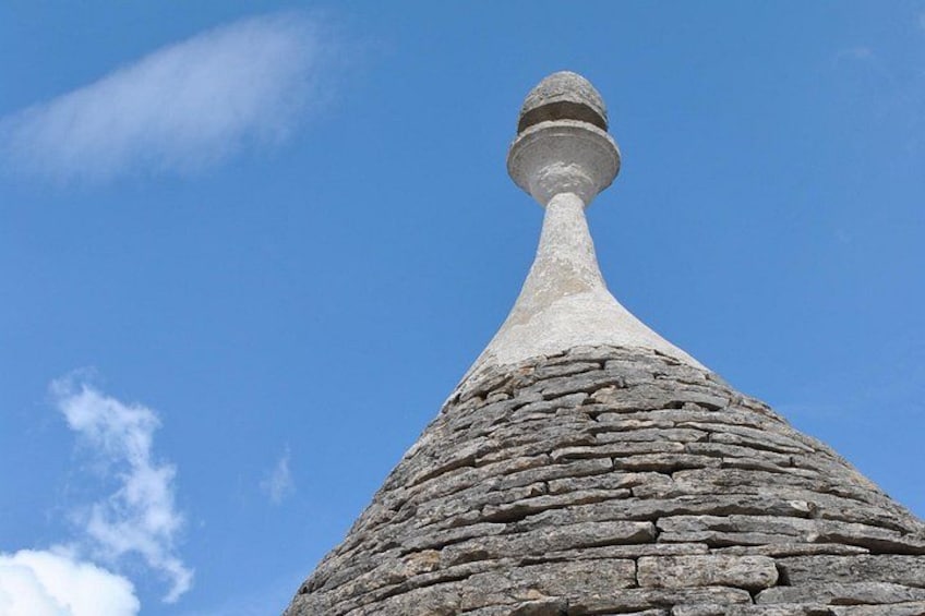 Un edificio in pietra con un tetto conico sotto un cielo azzurro limpido. 4