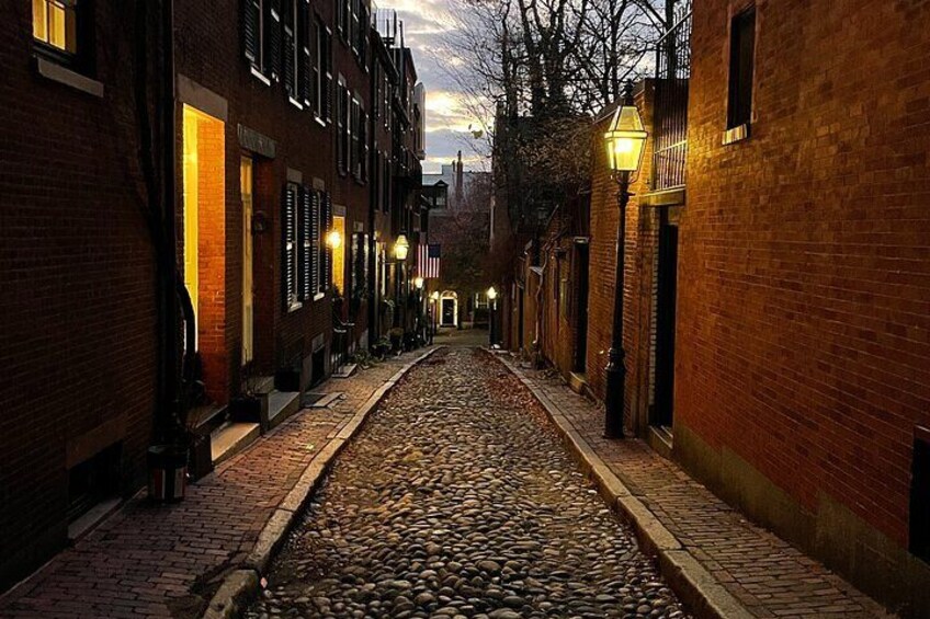 Una calle adoquinada flanqueada por edificios de ladrillo, iluminada por farolas. 5