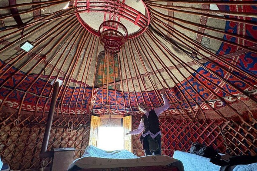 A traditional yurt with a patterned ceiling and a person standing inside. 4