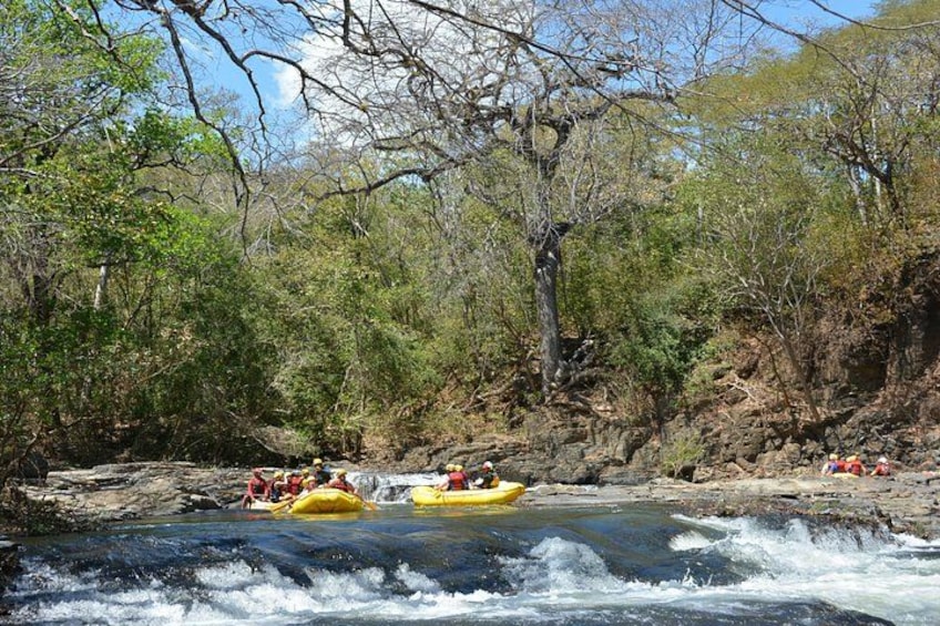 A river with rapids, surrounded by trees and rocky terrain. 2