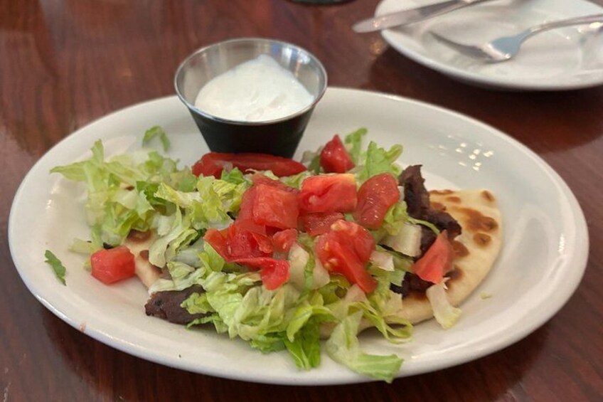 A plate of food with a salad, a piece of flatbread, and a small bowl of sauce. 5