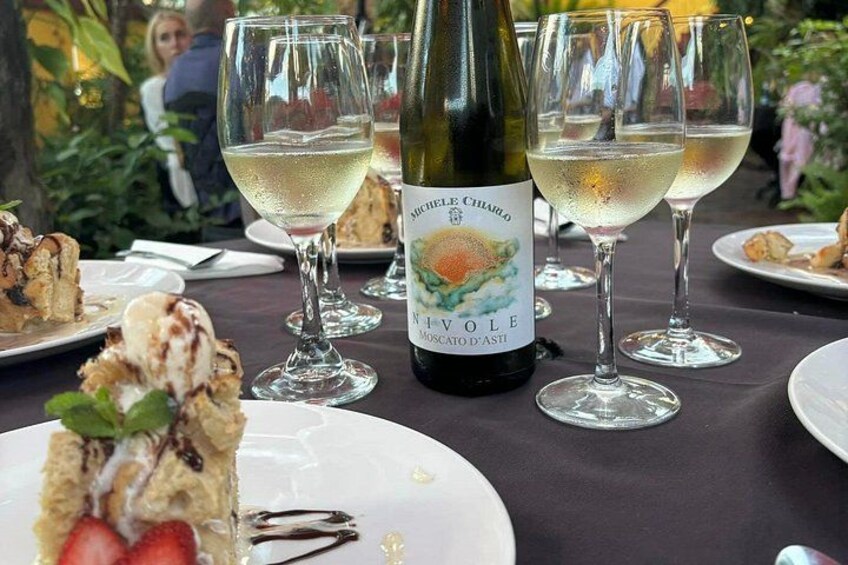 Una botella de vino, copas y postre sobre una mesa. 4