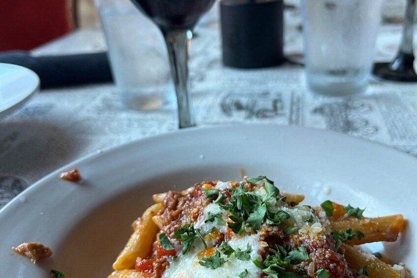Un plato de pasta con salsa roja, adornado con hierbas y queso. 2