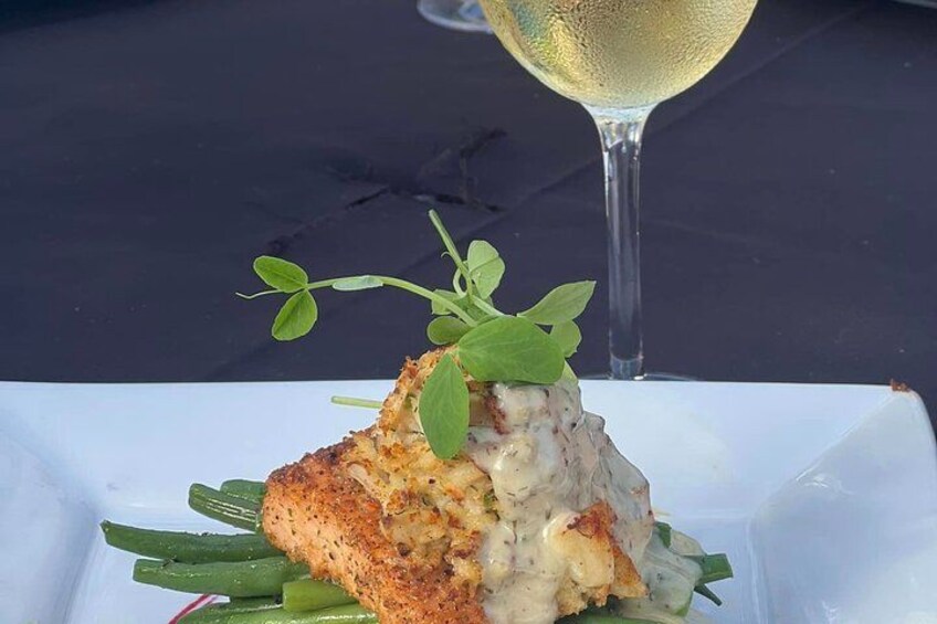 A plate with a piece of grilled chicken, green beans, and a garnish of microgreens, accompanied by a glass of white wine. 4