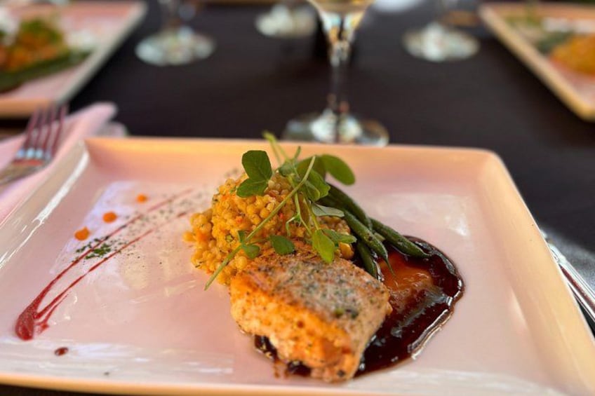 En firkantet tallerken med mad, muligvis fisk, pyntet med grønt og rød sauce. 3
