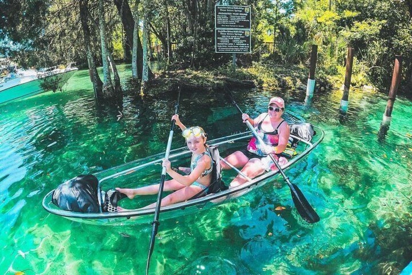 Two people in a canoe on clear water surrounded by trees. 2