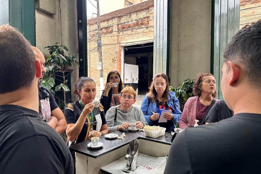 Un grupo de personas sentadas alrededor de una mesa en un café al aire libre. 4