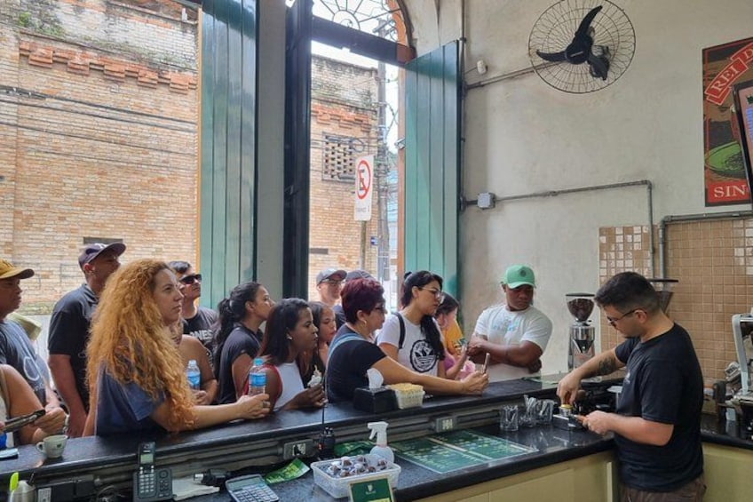 Un bar lleno de gente, con una pared de ladrillo y un ventilador en la pared. 2