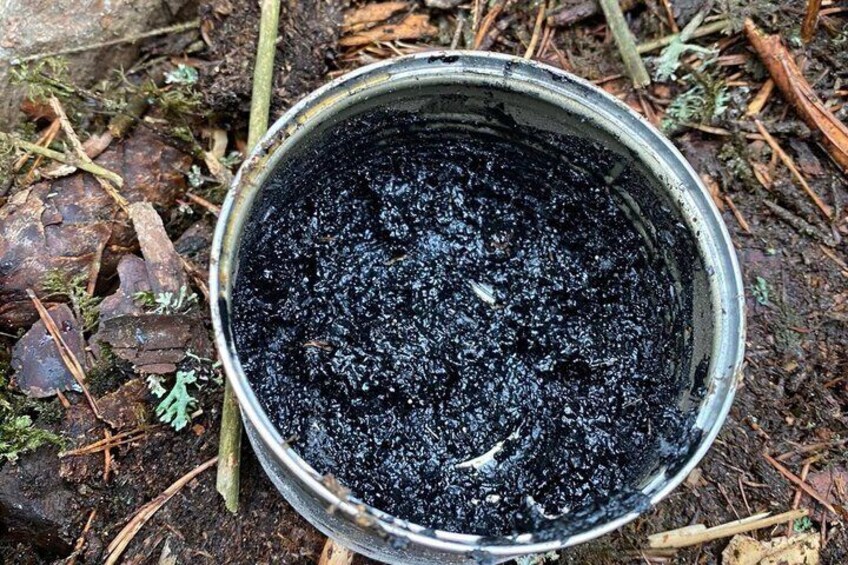 Un balde de metal lleno de tierra oscura o carbón sobre el suelo. 1