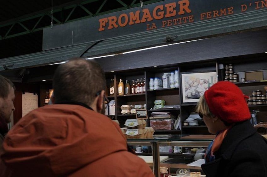 A storefront with shelves of bottled beverages and a sign that reads 'FROMAGER LA PETITE FERME D'IN.' 4