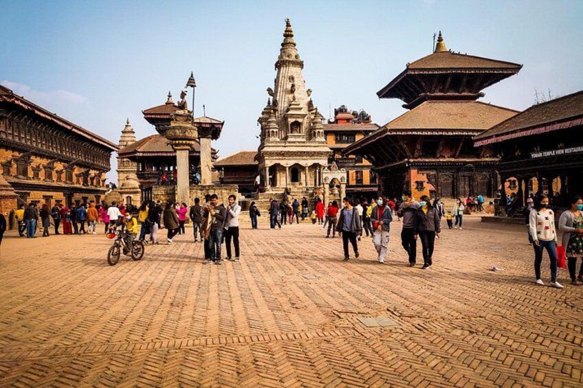 Una plaza animada con arquitectura tradicional, que incluye un templo destacado con una aguja. 2