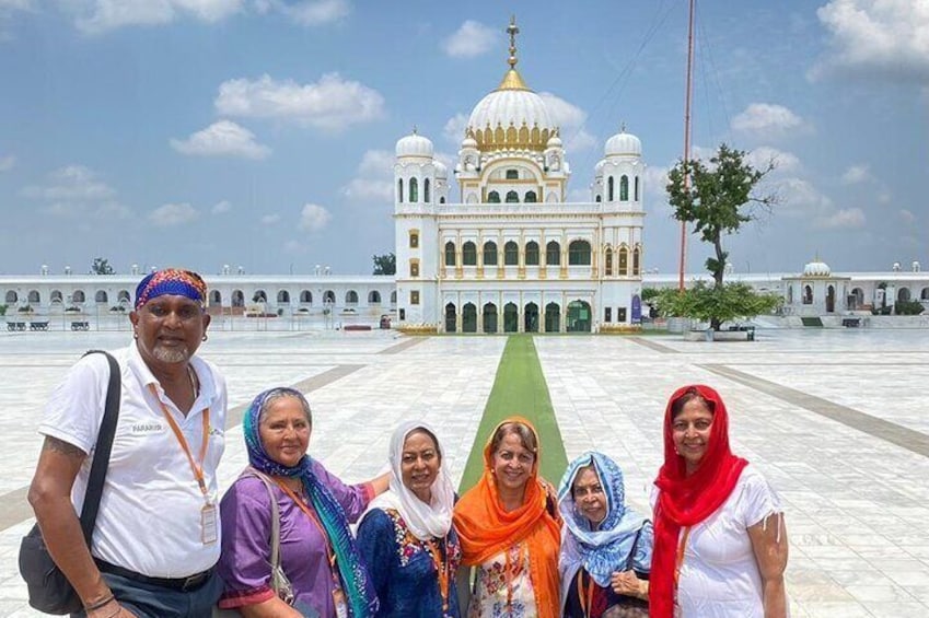 A group of people in front of a large white building with domes. 1