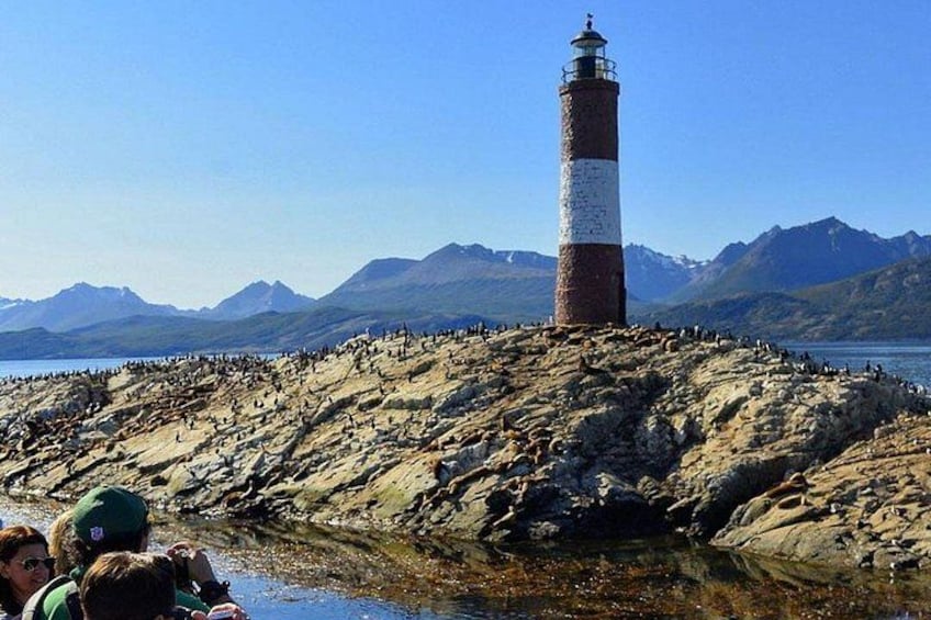 A lighthouse on a rocky outcrop with a mountainous backdrop. 5