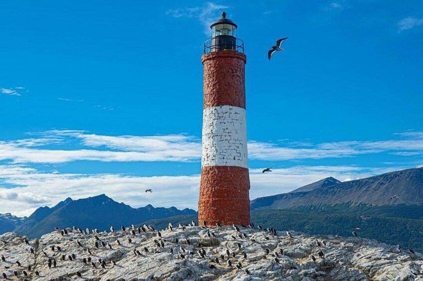 A lighthouse with a red and white striped tower, surrounded by rocky terrain and mountains in the background. 3