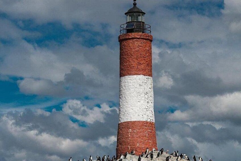 A tall lighthouse with a red and white striped pattern, surrounded by a rocky landscape and a cloudy sky. 2