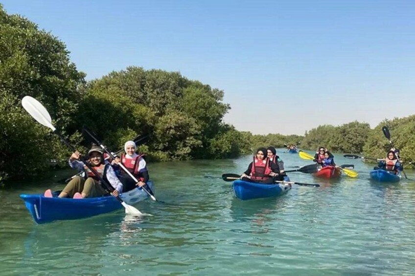 Menschen paddeln in einem ruhigen Fluss, der von dichtem Mangrovenwald gesäumt wird. 4