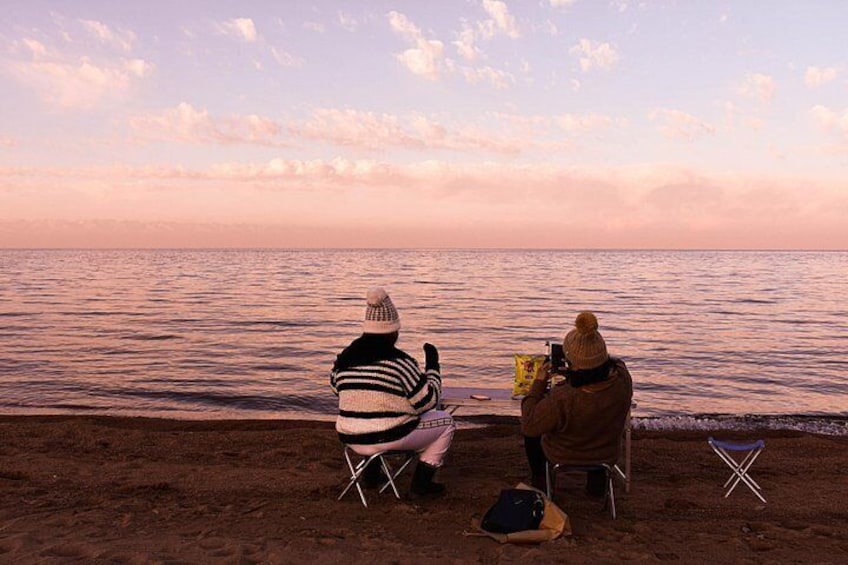 Two people sitting on chairs by the sea during sunset. 4