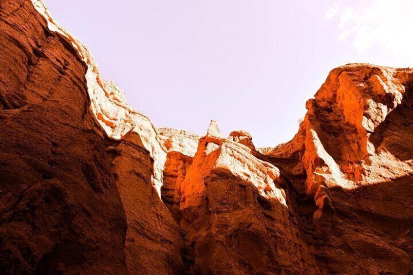 A canyon with reddish-brown rock formations and a clear sky. 3