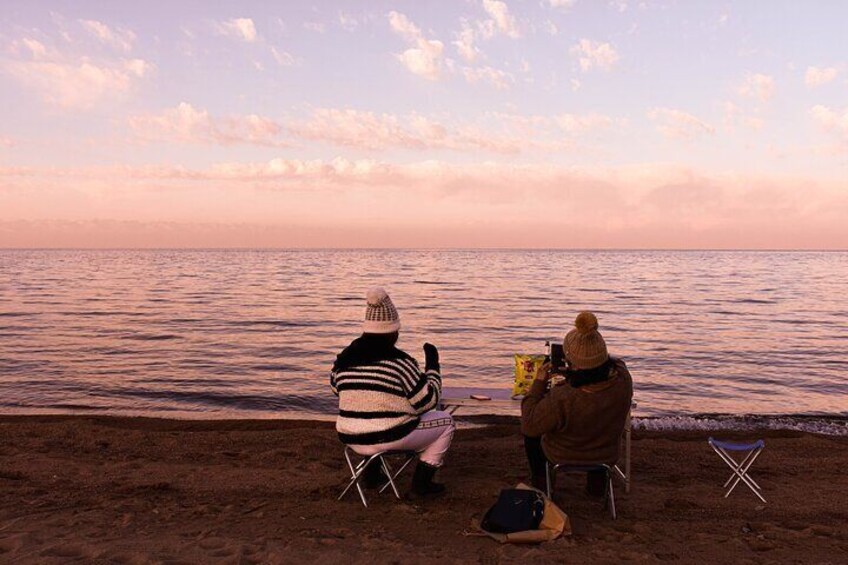 Two people sitting on chairs facing the sea during sunset. 4