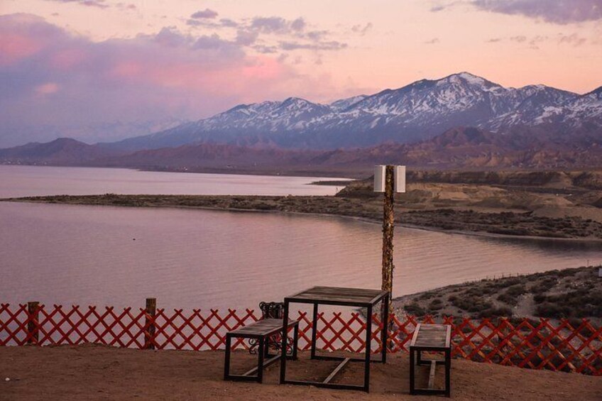 A lake with mountains in the background, a red fence, and a metal structure with a sign. 5