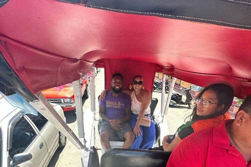 A group of people inside a vehicle with a red canopy, parked in a lot with other vehicles. 4