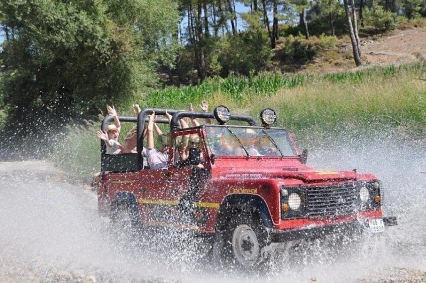 Un véhicule tout-terrain rouge roule dans l’eau, projetant des éclaboussures tout autour. 1