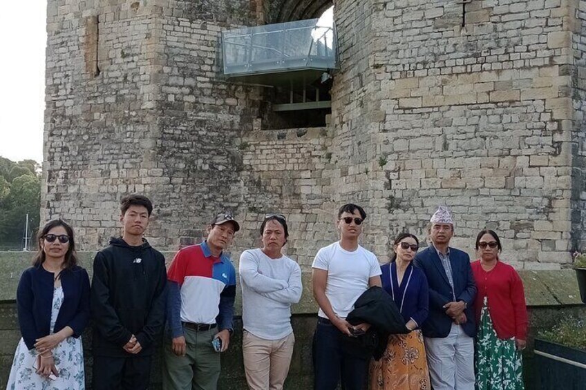 A group of people standing in front of an old stone building. 2