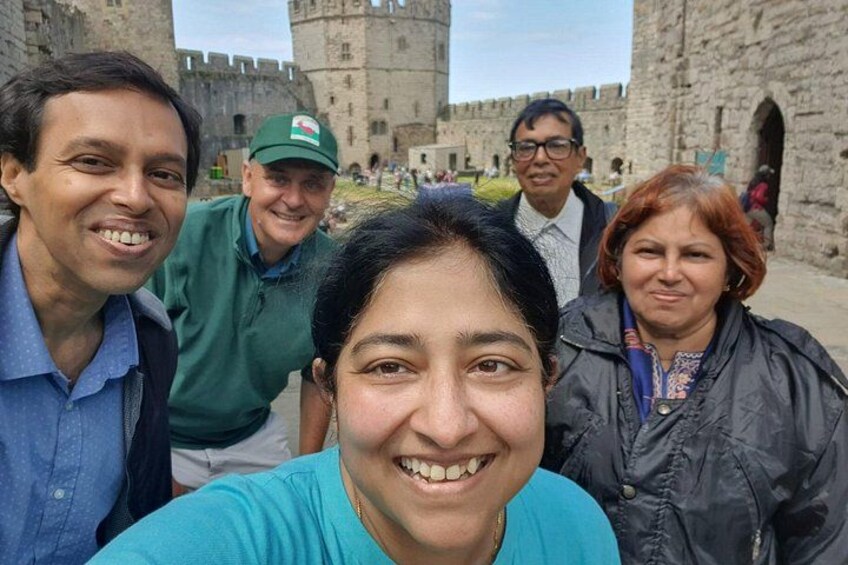 A group of people in front of a historic stone building with a tower. 3