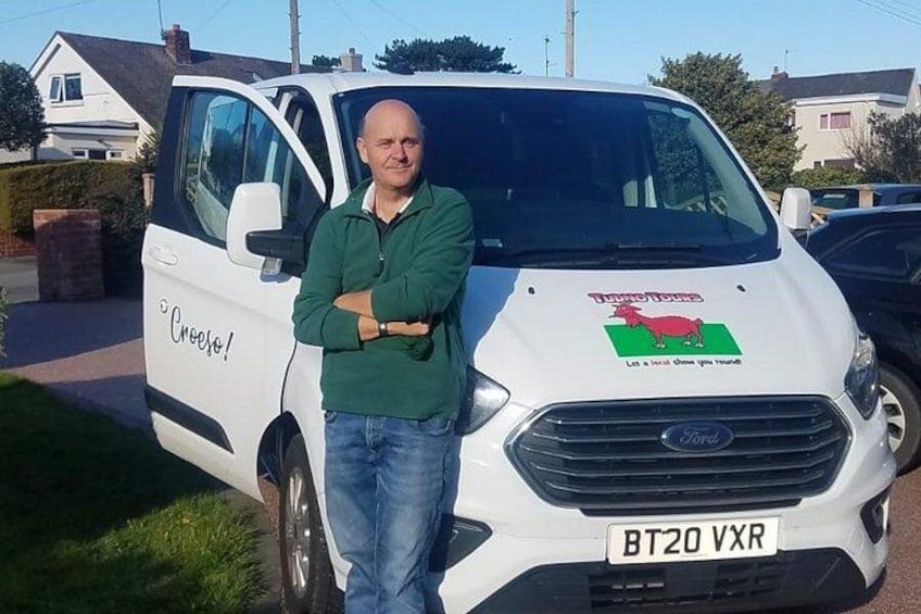 A man standing in front of a white van with a logo and text on the side. 2