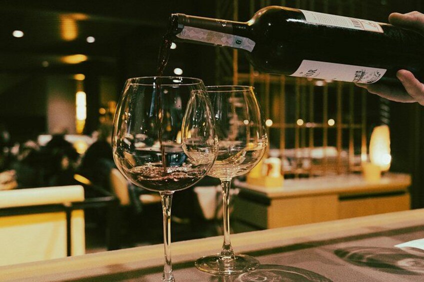 Une personne verse du vin dans deux verres au comptoir d’un bar. 5