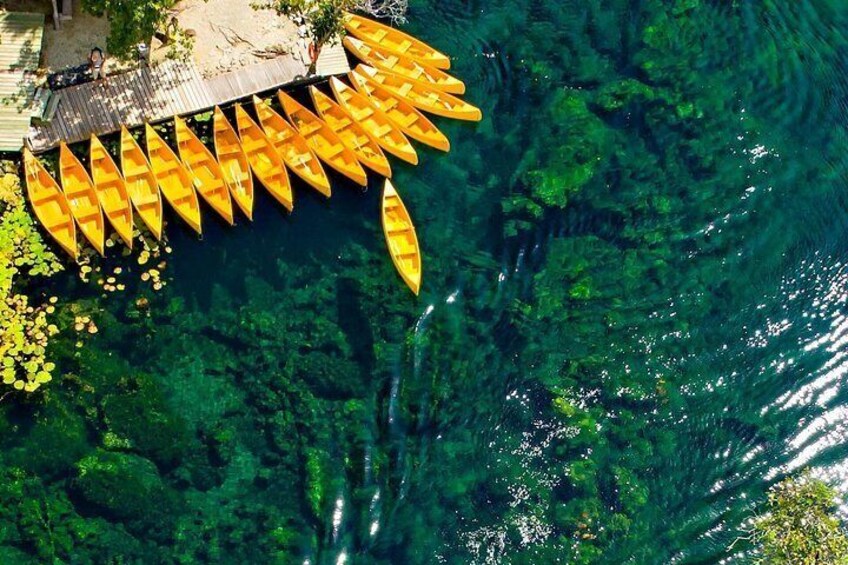 A clear water body with a dock and several yellow canoes. 2