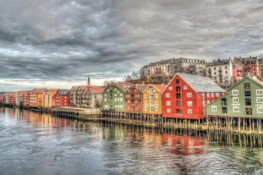 A waterfront with colorful buildings, a cloudy sky, and a distant castle. 3
