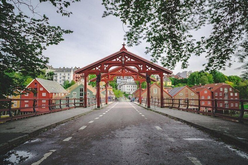 A red archway with a road leading through it, surrounded by trees and buildings. 5